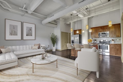 a living room with white couches and chairs and a kitchen
